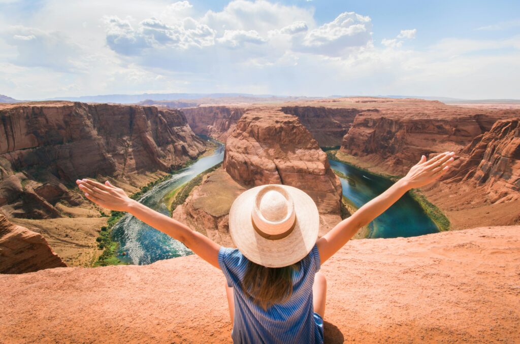 Woman Sitting on Cliff Overlooking Mountain